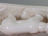 a sculpture of a cow laying down on a marble slab
