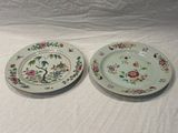 two plates with floral designs on them sitting on a white surface