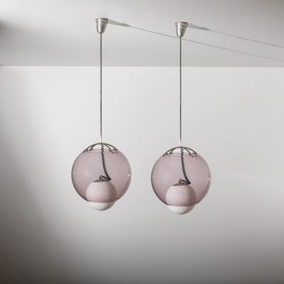 deux lampes en verre rose suspendues au plafond d'une pièce blanche