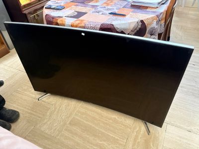 a flat screen tv sitting on the floor next to a bed