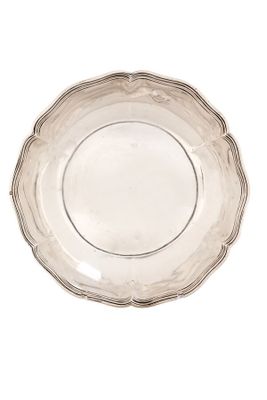 une assiette ancienne en argent au bord festonné sur fond blanc
