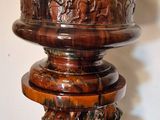 a wooden pedestal with carvings on it on a wooden floor