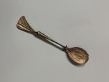 a close up of a brass spoon with a leaf on it