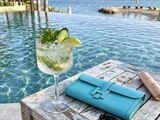 a drink and sunglasses on a table by the pool