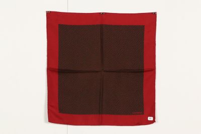 une écharpe carrée marron et rouge accrochée à un mur blanc