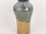 un vase vert avec un socle marron sur fond blanc