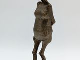 bronze statue of a woman standing on a base with a hat on her head