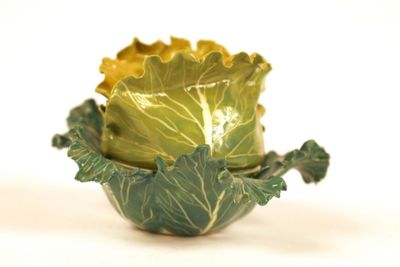a green cabbage bowl sitting on a white surface