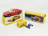 deux petites voitures et une boîte de jouets posées sur une surface blanche