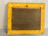 an old yellow frame with a blackboard in it on a white surface
