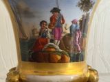 a gold vase with a picture on it on a table