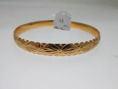 gros plan d'un bracelet en or sur une surface blanche