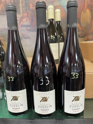 three bottles of wine are sitting on a table in front of a painting