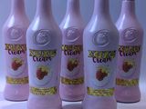 six bouteilles d'une délicieuse crème aux fraises posées sur un plan de travail blanc