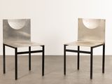 two chairs with a metal back and seat in a white room