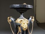a black and gold pedestal with a lion head on it