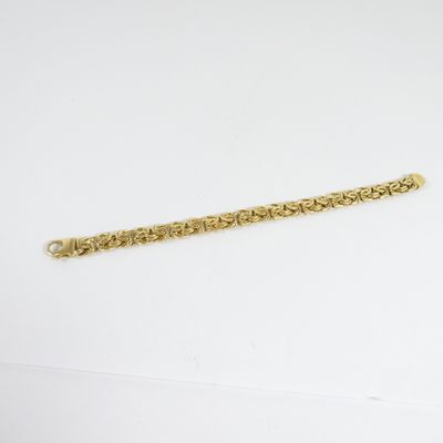gros plan d'un bracelet en or sur une surface blanche