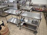 de nombreuses tables en acier inoxydable dans une cuisine, sur lesquelles sont posés de nombreux objets