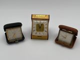 trois horloges miniatures posées les unes à côté des autres sur une surface blanche