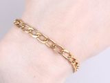a close up of a woman ' s hand wearing a gold chain bracelet