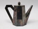an old silver teapot with a black handle on a white surface