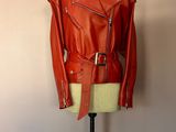 une veste en cuir rouge posée sur un mannequin devant un mur rose