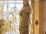 une statue représentant une femme tenant un bébé dans ses bras, posée sur une table devant une fenêtre