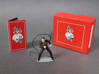 figurine représentant un homme en costume noir, muni d'un micro et d'une boîte rouge