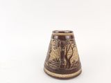 a brown vase with a design on it on a white surface