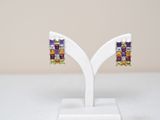 une paire de boucles d'oreilles en pierres multicolores posées sur un présentoir blanc