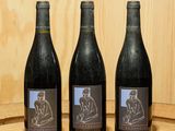trois bouteilles de vin posées sur un tonneau en bois
