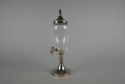 un ancien distributeur d'eau en verre plaqué argent, posé sur un socle