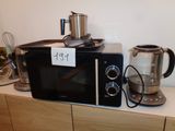 un micro-ondes noir posé sur un plan de travail, à côté d'une cafetière