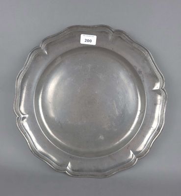 assiette en argent plaqué, à bord festonné, sur fond gris, avec une étiquette blanche