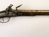 un vieux pistolet avec une poignée en bois sur une surface blanche