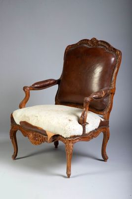 une vieille chaise avec une assise en cuir et un coussin blanc