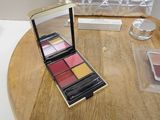 a wooden table with a silver purse and a makeup palette on it