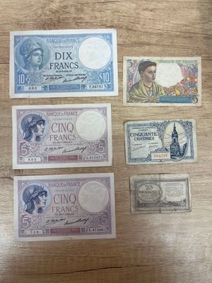six different french bank notes on a table with a wooden table top