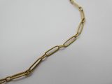 gros plan d'un collier à chaîne en or sur une surface blanche