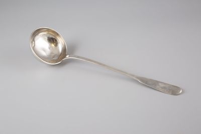 une cuillère en argent posée sur une surface blanche, avec une petite cuillère au milieu