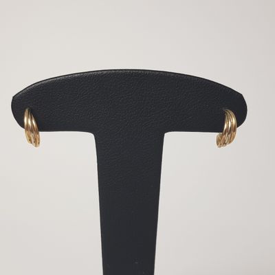 a pair of gold hoop earrings on a black stand