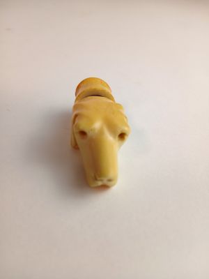 une petite figurine d'animal jaune posée sur une surface blanche
