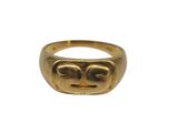 un gros plan d'une bague en or sur laquelle est gravé un visage