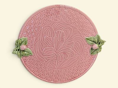 a pink plate with green leaves on it on a white surface