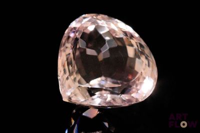 a pink diamond on a black surface with a black background