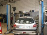 une voiture argentée posée sur un pont élévateur dans un garage