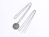 three silver necklaces on a white surface with a chain
