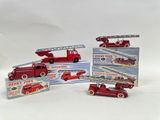 several toy fire trucks are lined up on a white surface
