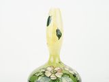 a green vase with flowers on it on a white surface