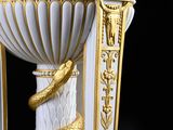 un vase blanc et doré surmonté d'un serpent